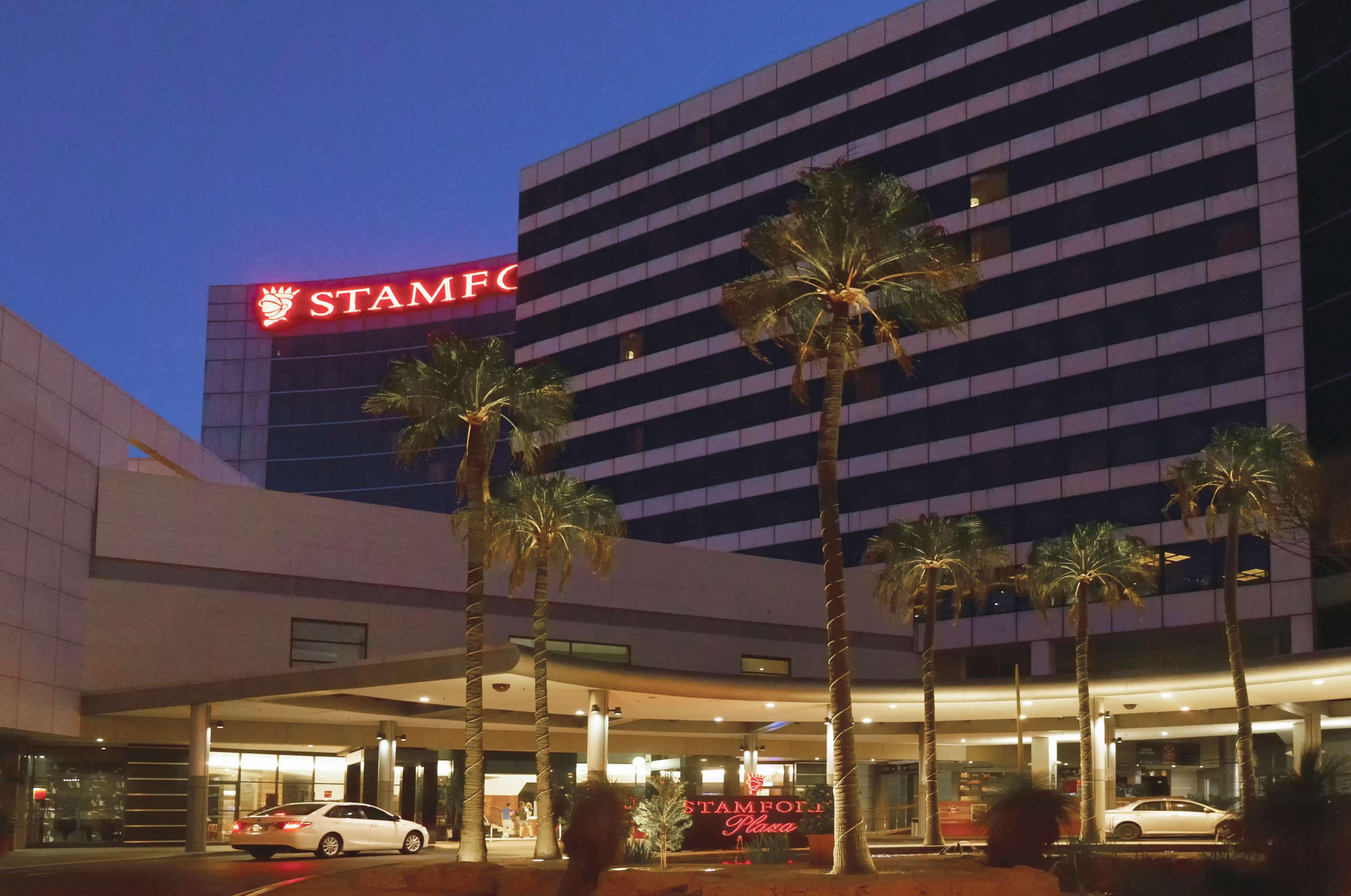 Stamford Plaza Sydney Airport Hotel & Conference Centre Exterior photo The photo shows a hotel building illuminated at night, featuring the name "STAMFORD" prominently displayed in bright red lights on top. The architecture includes a multi-story structure with large windows. In front of the building, there are palm tre